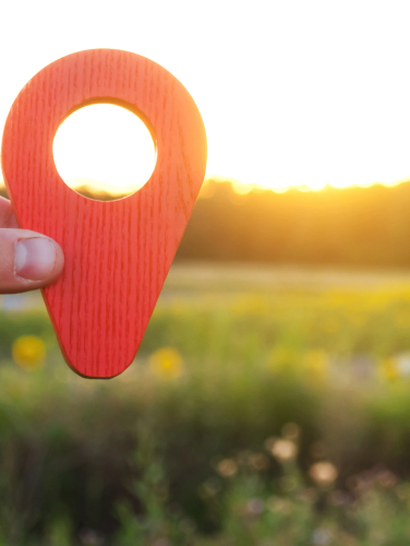 Image of someone holding a place locator icon in field.