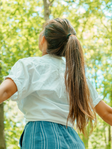 A young woman enjoying the fresh air of a forest.